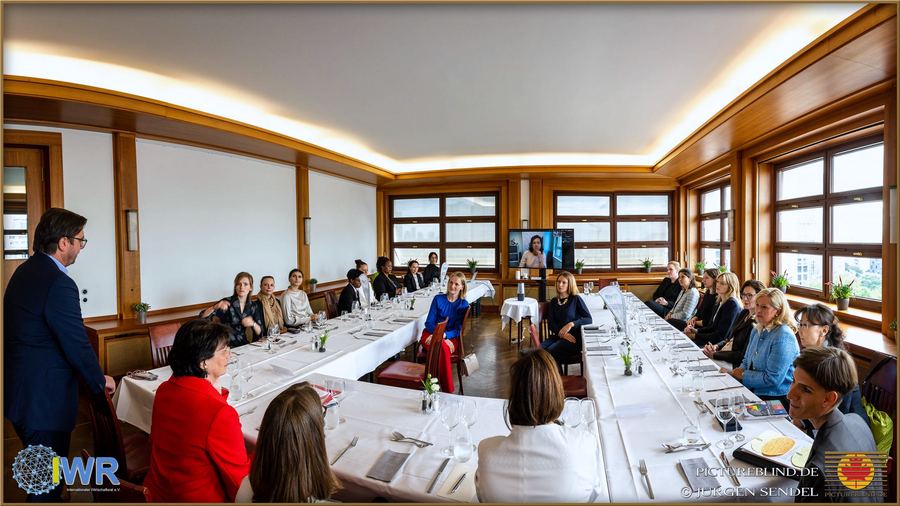 Langer, festlich eingedeckter Konferenztisch in einem hellen Saal, an dem Teilnehmerinnen und Teilnehmer einer Veranstaltung sitzen.